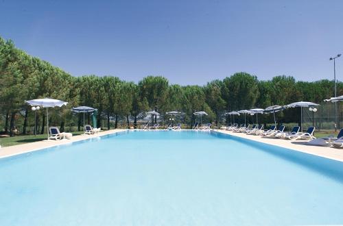 uma grande piscina com cadeiras e guarda-sóis em Ranch Hotel em Scarlino