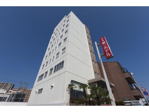 Onomichi Daiichi Hotel في أونوميتشي: مبنى أبيض طويل مع علامة أمامه