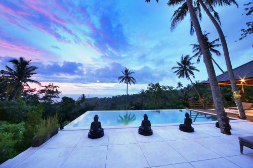 a group of people sitting in meditation by a swimming pool at Villa Marley in Senggigi 