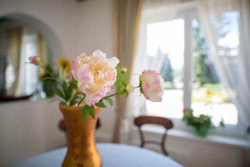 un jarrón con flores rosas sentado en una mesa en Villa Konstanze, en Velden am Wörthersee