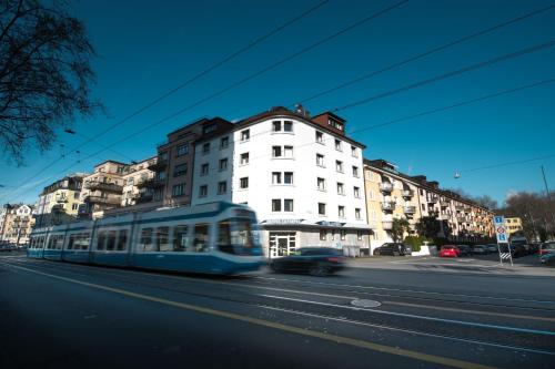 un tram blu in una strada di città con edifici di Olympia Hotel Zurich a Zurigo