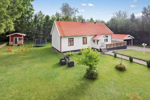 una pequeña casa blanca con parque infantil en un patio en Ferienhaus am Mycklaflon, en Eksjö