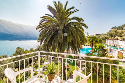 einen Balkon mit einer Palme und Blick auf das Wasser in der Unterkunft Hotel Riviera Panoramic Green Resort in Limone sul Garda