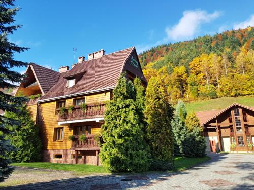 une grande maison en bois avec un toit en gambrel dans l'établissement Rezydencja Leśny Dwór, à Piwniczna-Zdrój