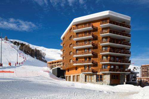 un bâtiment dans la neige à côté d'une piste de ski dans l'établissement Araucaria Hotel & Spa, à La Plagne