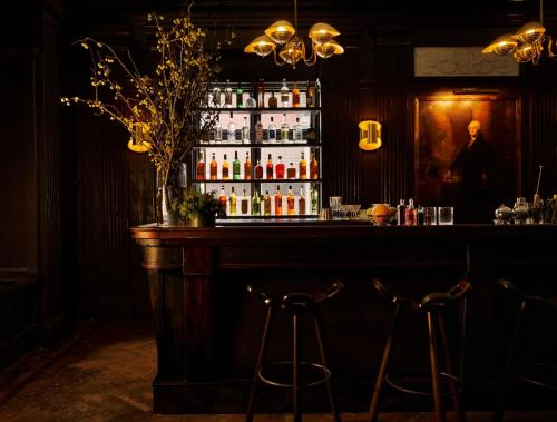 a bar with two stools in a room with alcohol at Freehand New York in New York