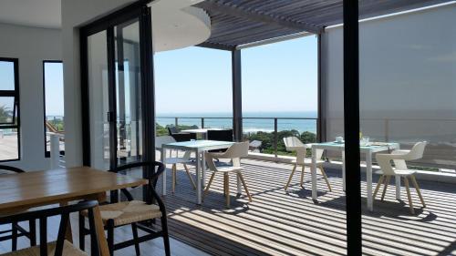 een balkon met tafels en stoelen en uitzicht op de oceaan bij Ocean Vista Boutique Guest House in Durban