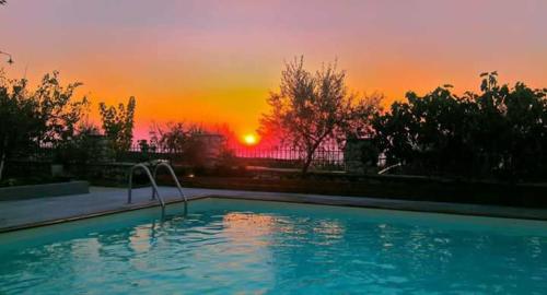 a swimming pool with a sunset in the background at Zephyros Rooms And Apartments in Drymon