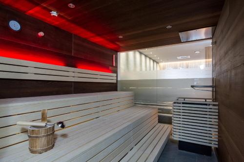 sauna z drewnianymi ławkami i czerwonym oświetleniem w obiekcie Hotel Post Wrann w mieście Velden am Wörthersee