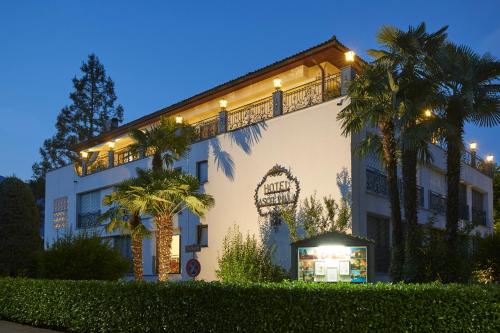 un gran edificio blanco con palmeras delante en Hotel Ascovilla Charming Hideway, en Ascona