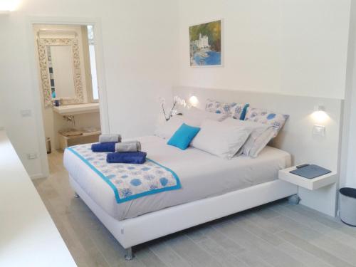 a white bedroom with a white bed with blue pillows at Hotel Madalù in Rimini