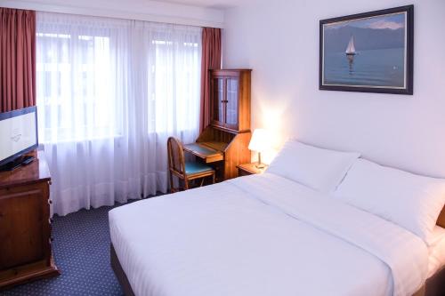 a hotel room with a large bed and a television at Hotel Sagitta in Geneva