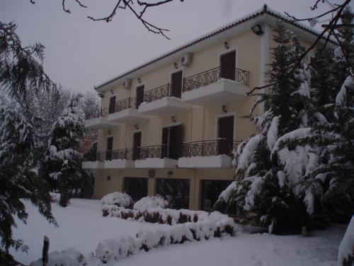 een groot huis met sneeuw op de grond bij Aroanios Hotel in Klitoria