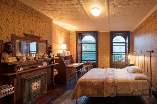 een slaapkamer met een bed, een bureau en ramen bij The Harlem Flophouse in New York