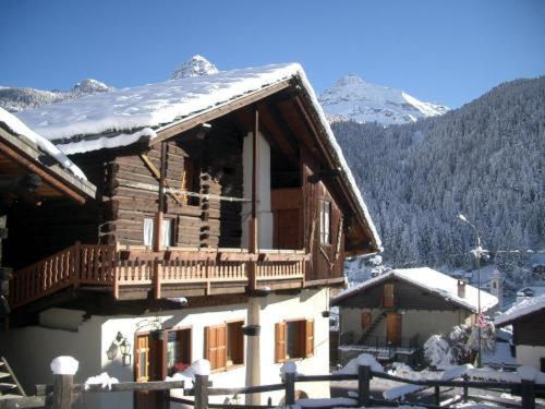 a log cabin with a balcony and snow on the roof at Le Vieux Rascard Chambres d'Hotes in Champoluc