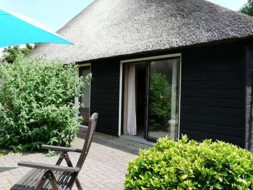 a wooden chair sitting in front of a black house at De Galeriet Giethoorn in Giethoorn