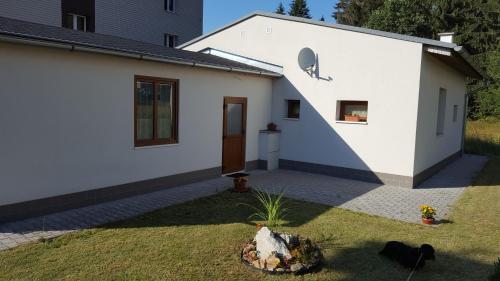 a white house with a door and a yard at Apartmán Srní in Srní