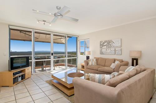 a living room with a couch and a tv at Bali Hai Apartments Noosa in Noosa Heads