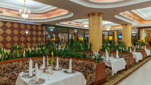 uma sala de jantar com mesas brancas e plantas em Hotel Gołębiewski Mikołajki em Mikołajki