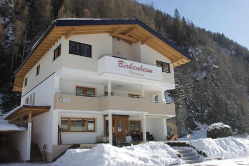 a building in the snow with a mountain at Birkenheim Widmann in Längenfeld