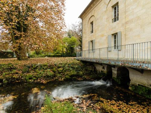 Hôtel Le Domaine Du Moulin de Monjous في جرادينيا: جسر فوق تيار بجوار مبنى