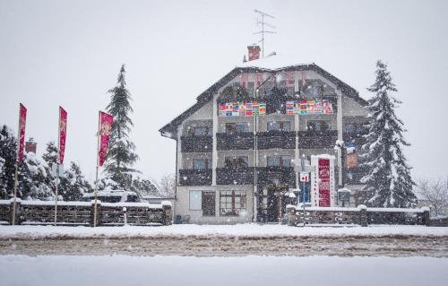 een groot gebouw in de sneeuw met vlaggen bij Hotel Krona Domžale in Domžale