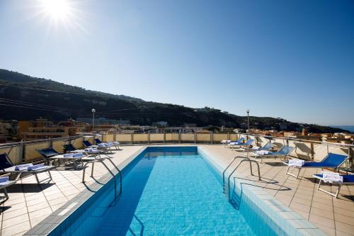 una piscina sul tetto di un edificio con sedie a sdraio di Grand Hotel Cesare Augusto a Sorrento