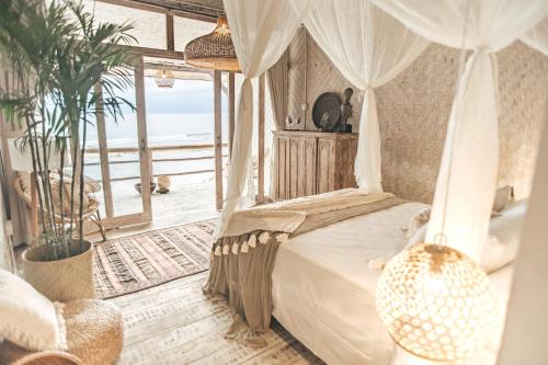 een slaapkamer met een hemelbed en uitzicht op de oceaan bij Dreamsea Bali in Uluwatu