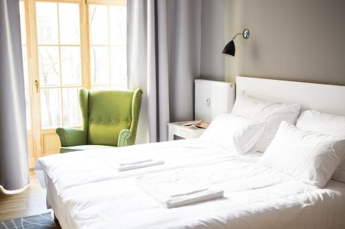 una camera con un letto bianco e una sedia verde di Riga Lux Apartments - Skolas a Riga