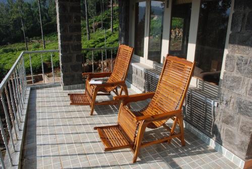 twee houten stoelen op een veranda bij Relaxing 2 B/R Estate House, Deenaty, Tamil Nadu in Coimbatore