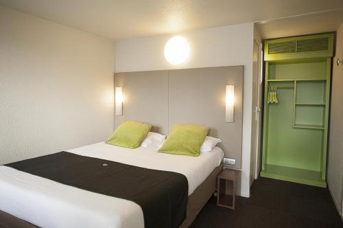 ein Schlafzimmer mit einem großen Bett mit zwei grünen Kissen in der Unterkunft Campanile Bordeaux Nord - Le Lac in Bordeaux