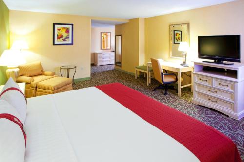 Holiday Inn Chantilly-Dulles Expo Airport, an IHG Hotel في شانتيلي: غرفة الفندق بسرير كبير ومكتب