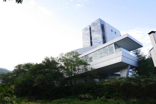 un edificio en una colina con árboles delante de él en Takamiya Hotel Rurikura Resort, en Zao Onsen