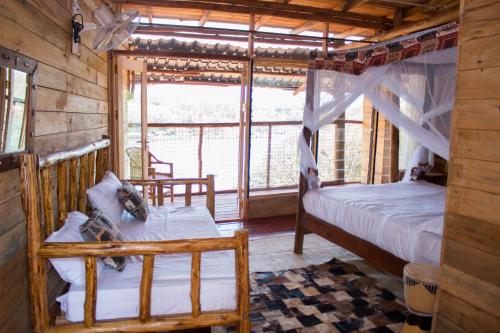 een slaapkamer met 2 bedden en een raam in een hut bij Living Waters Resort in Jinja