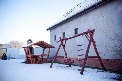 un parco giochi nella neve accanto a un edificio di Adonisz Vendégház a Mórahalom