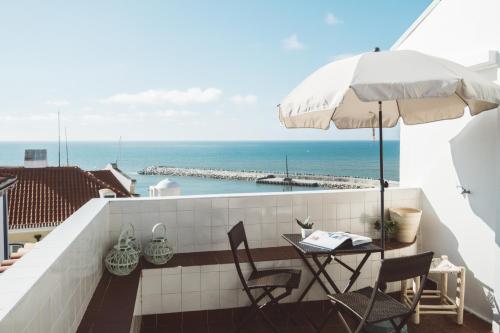 een balkon met een tafel en stoelen en een parasol bij Apartamento 2 quartos by WOT Ericeira Lodge in Ericeira