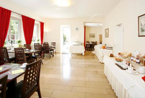 a dining room with tables and chairs and red curtains at Hotel Biederstein am Englischen Garten in Munich