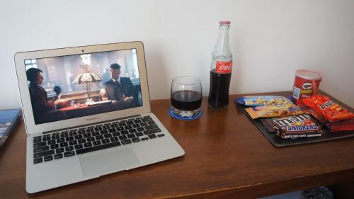 a laptop computer sitting on a wooden table with a drink at Palm Beach Plaza Hotel in Montevideo