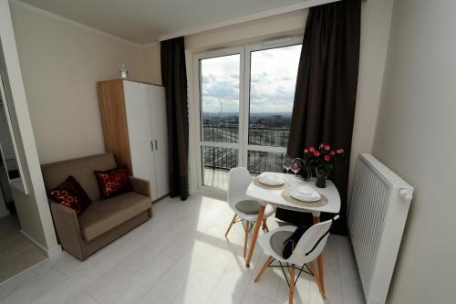 a living room with a table and chairs and a window at Romantic Sky Apartment- 15th floor in Kraków