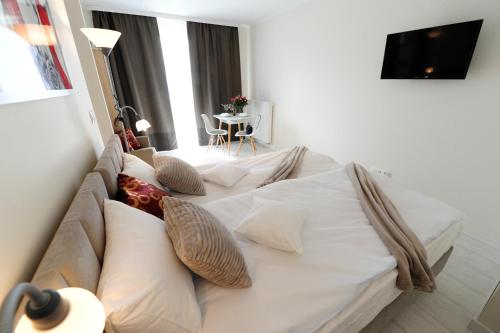 a bedroom with a white bed with pillows and a table at Romantic Sky Apartment- 15th floor in Kraków