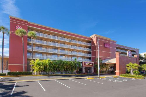 um grande edifício vermelho com palmeiras num parque de estacionamento em Ramada by Wyndham Tampa Westshore Airport South em Tampa