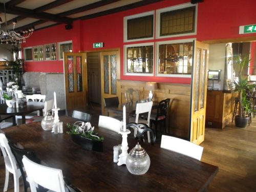 een eetkamer met een houten tafel en witte stoelen bij De Gouden Karper in Rustenburg