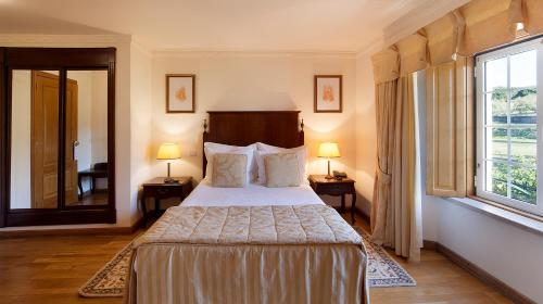 a bedroom with a bed and a large window at Turim Club Azeitao Hotel in Setúbal