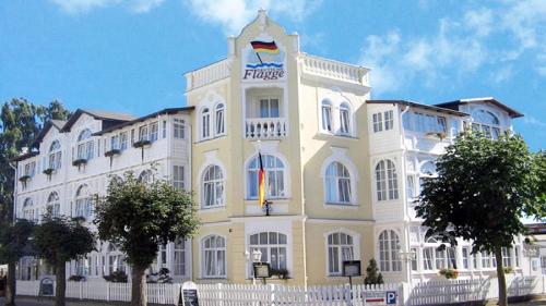 un grand bâtiment jaune et blanc avec un panneau sur celui-ci dans l'établissement Hotel Deutsche Flagge, à Binz