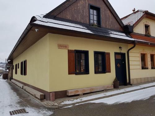 uma casa amarela com uma porta azul na neve em Privat pri Hradbach em Levoča