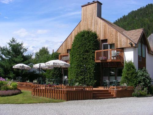 um edifício com varanda, mesas e cadeiras em Auberge du Jardin em Petit-Saguenay