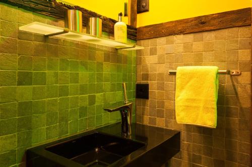 a green tiled bathroom with a sink and a towel at Chalet Schtuba in Zermatt