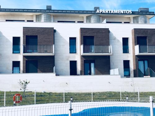 um edifício de apartamentos com uma piscina em frente em Costa Quebrada Apartamentos em Soto de la Marina