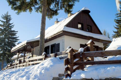 ein schneebedecktes Haus mit einem Zaun in der Unterkunft Chalupy Na Rališce in Horní Bečva