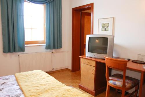 una camera con scrivania, TV e letto di Guest House Arvaj a Kranj